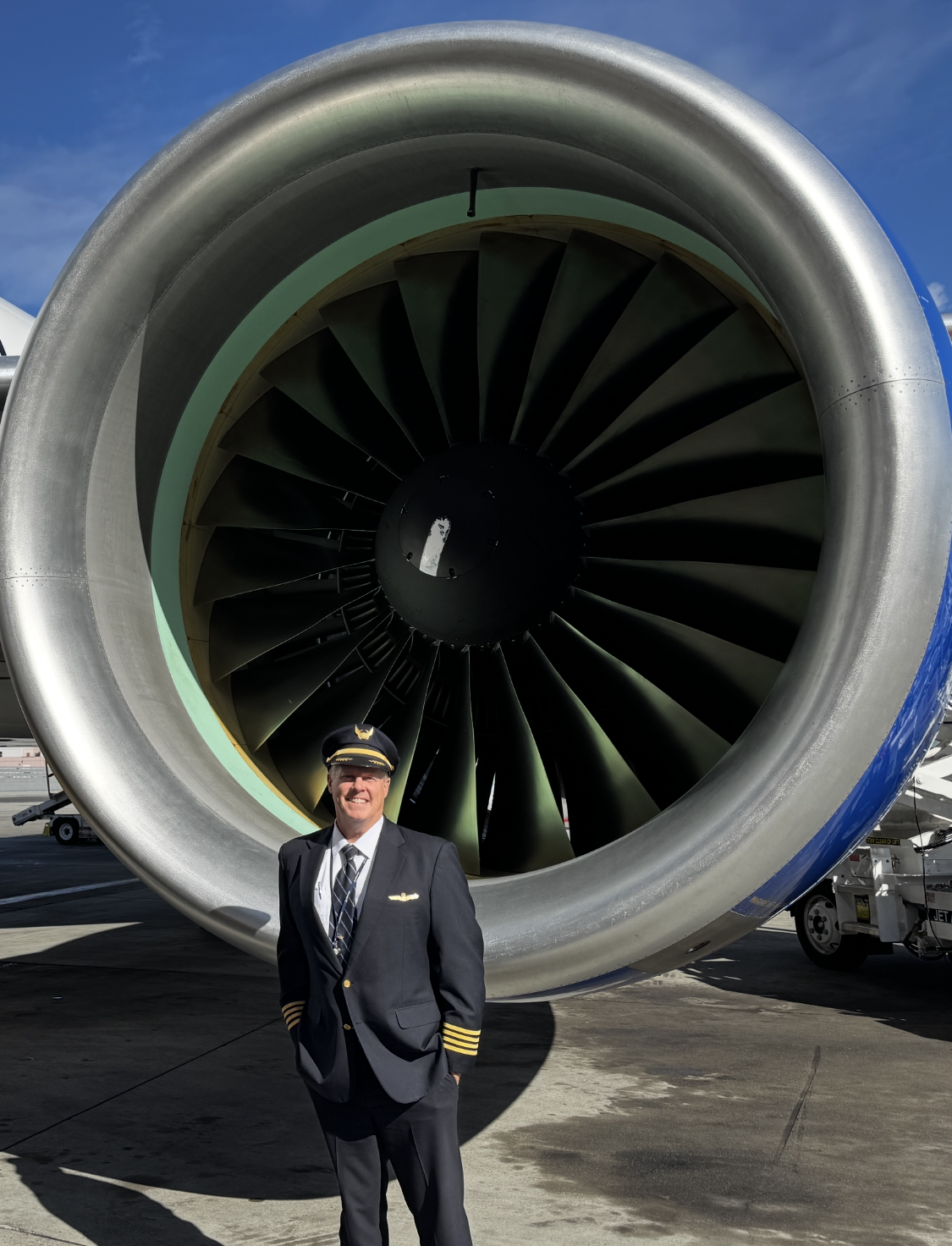 Brian Hope in his pilot uniform, standing in front of an aircraft engine.